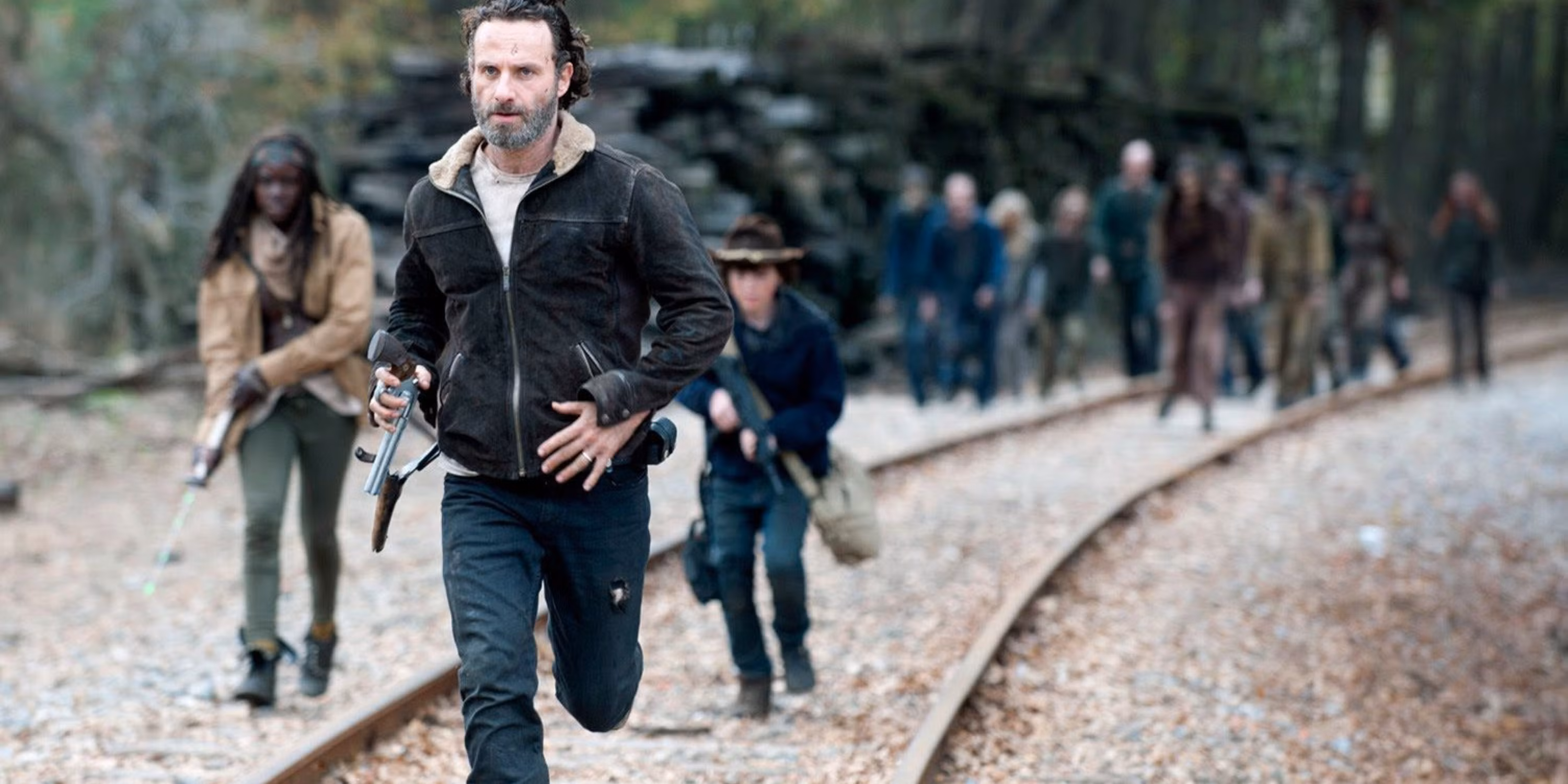 Rick, Carl, and Michonne running on train tracks in The Walking Dead